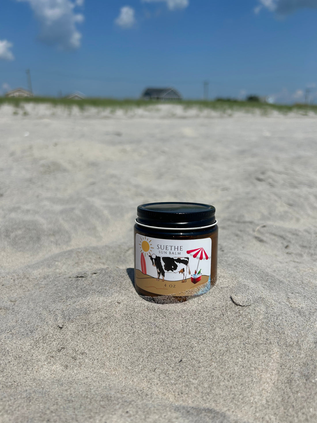 Tallow-based mineral sun balm with zinc oxide photographed on beach sand in natural light